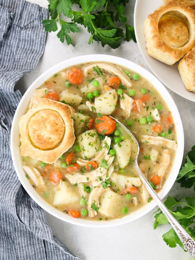Chicken Pot Pie soup in a bowl with a baked puff pastry shell on top.