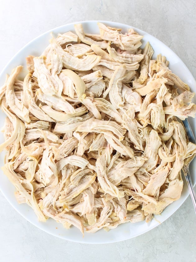 Chicken breasts cooked and shredded on a plate.