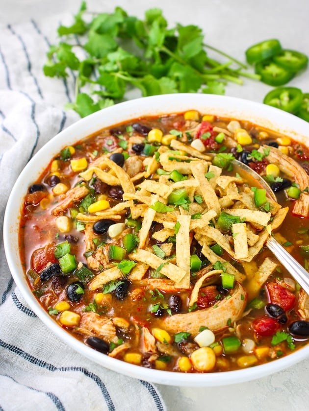 A delicious chicken tortilla soup recipe in a bowl garnished with tortilla strips.