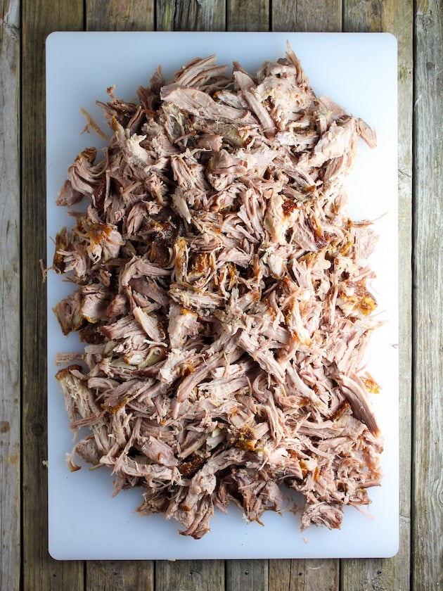 Shredded pork butt on a cutting board.