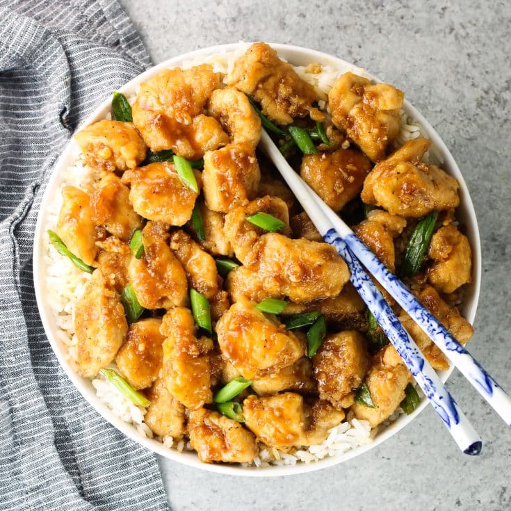 A bowl of Mongolian Chicken with rice and chopped green onions.
