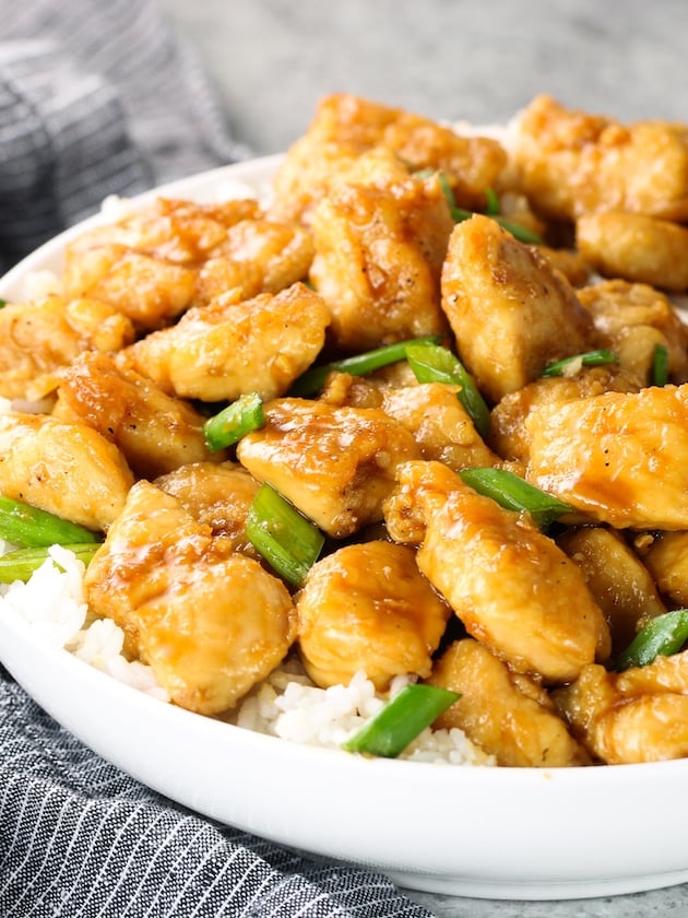 A bowl with Mongolian chicken and green onions over white jasmine rice.