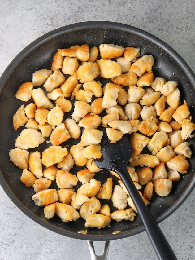 Chopped chicken tenders cooked in a skillet.