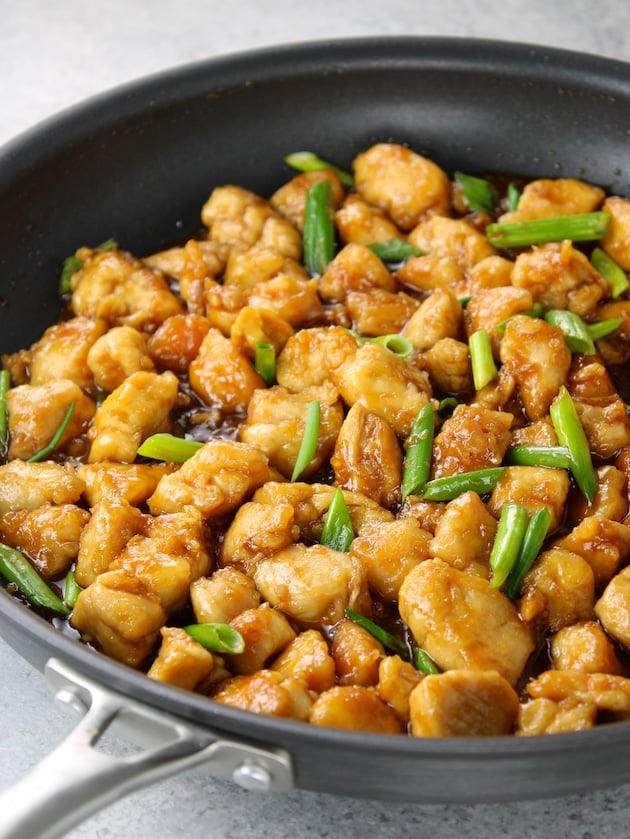 Cut-up chicken tenders cooked in a skillet with Mongolian Chicken sauce and green onions.