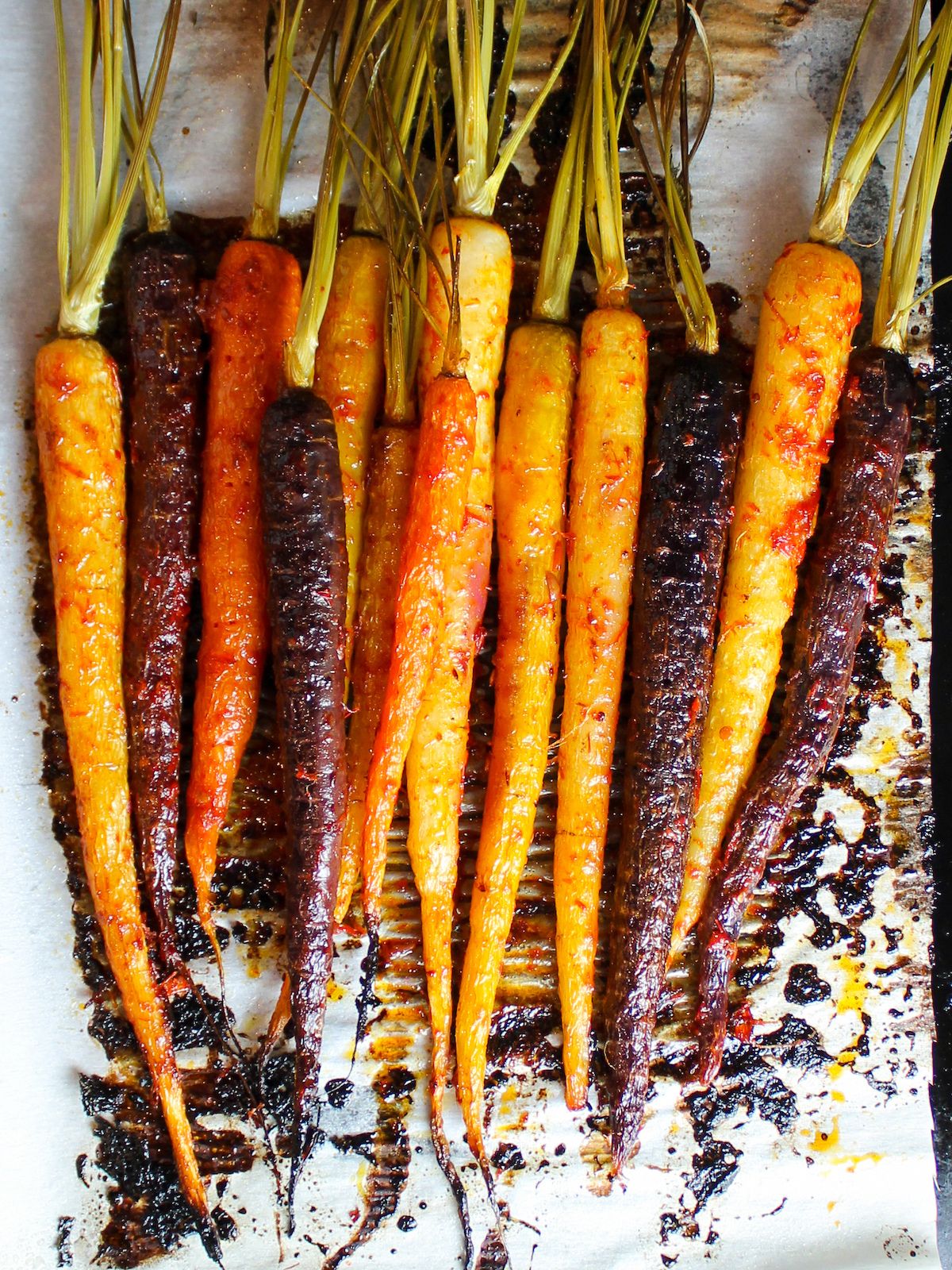 Carrots tossed in harissa sauce and roasted on a baking sheet.