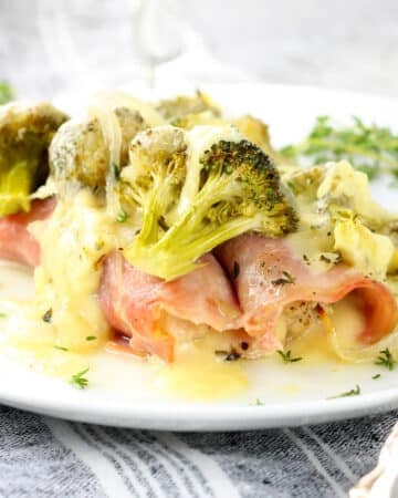 A plate with chicken cordon blue casserole with broccoli.