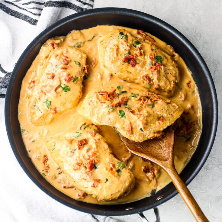 A photo of cooked chicken breasts in a large saucepan with a creamy Marry Me Chicken sauce.