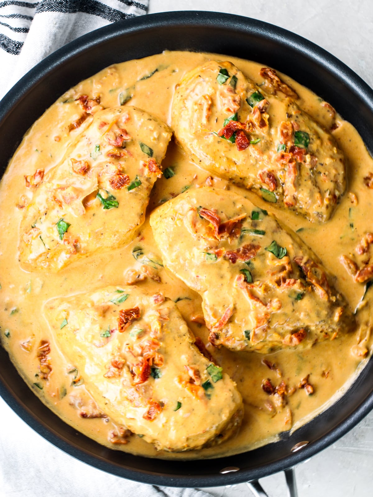 An over-the-top view of a saucepan with cooked chicken breasts in a creamy sun-dried tomato sauce.