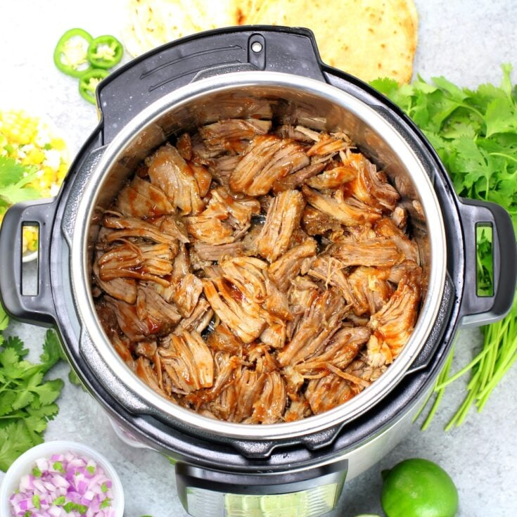 An Instant Pot with cooked pulled pork carnitas meat.
