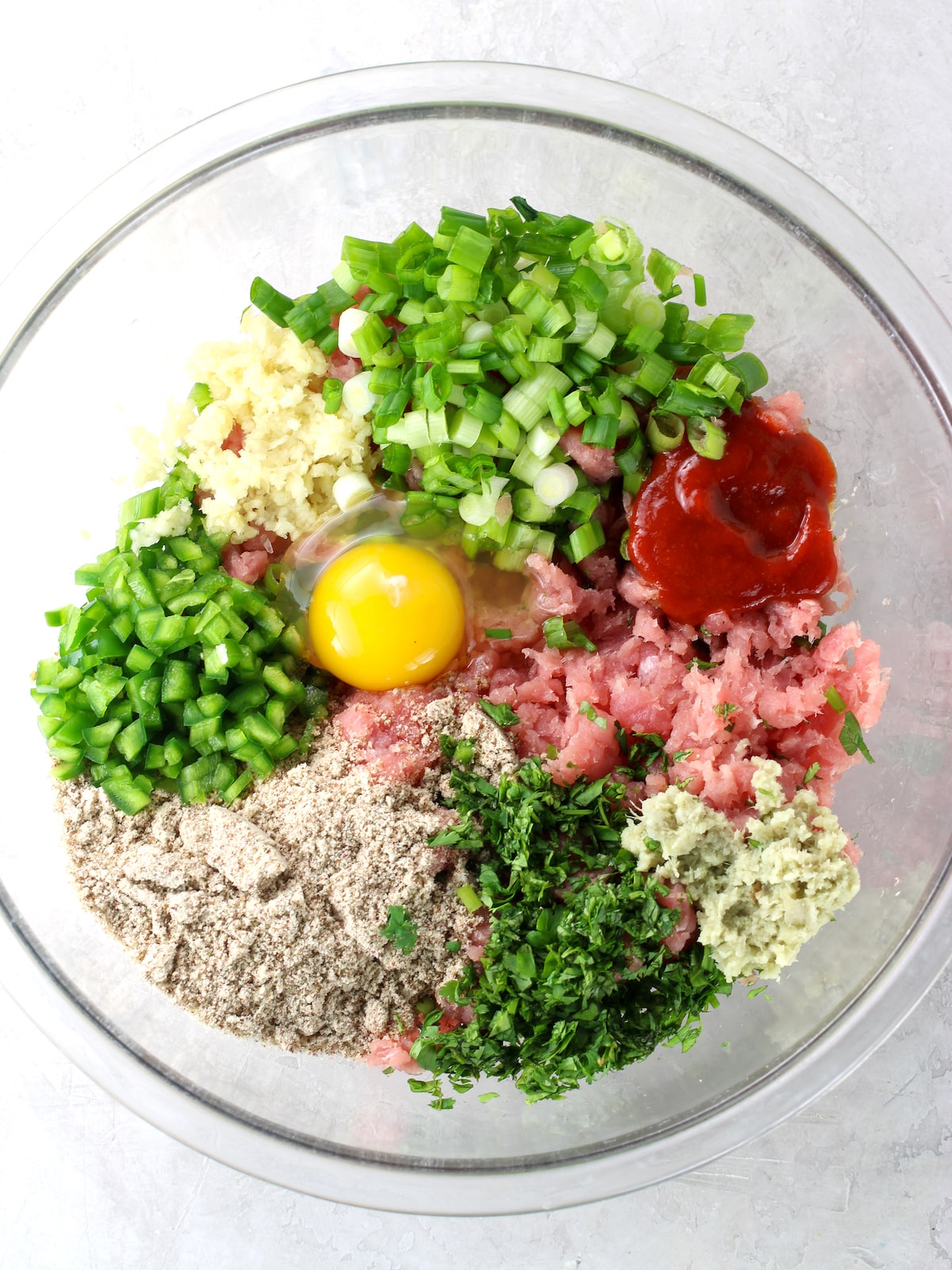 A large glass bowl with the burger ingredients before mixing them together.