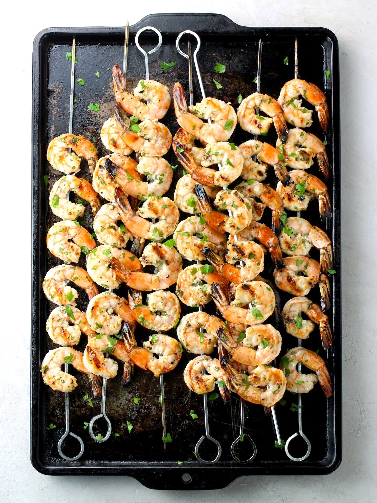 Skewers of grilled shrimp on a baking sheet.