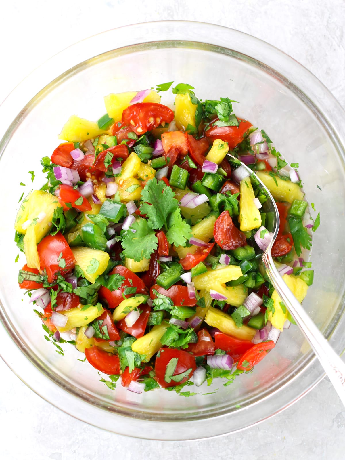 A glass bowl of pineapple salsa mixed together.