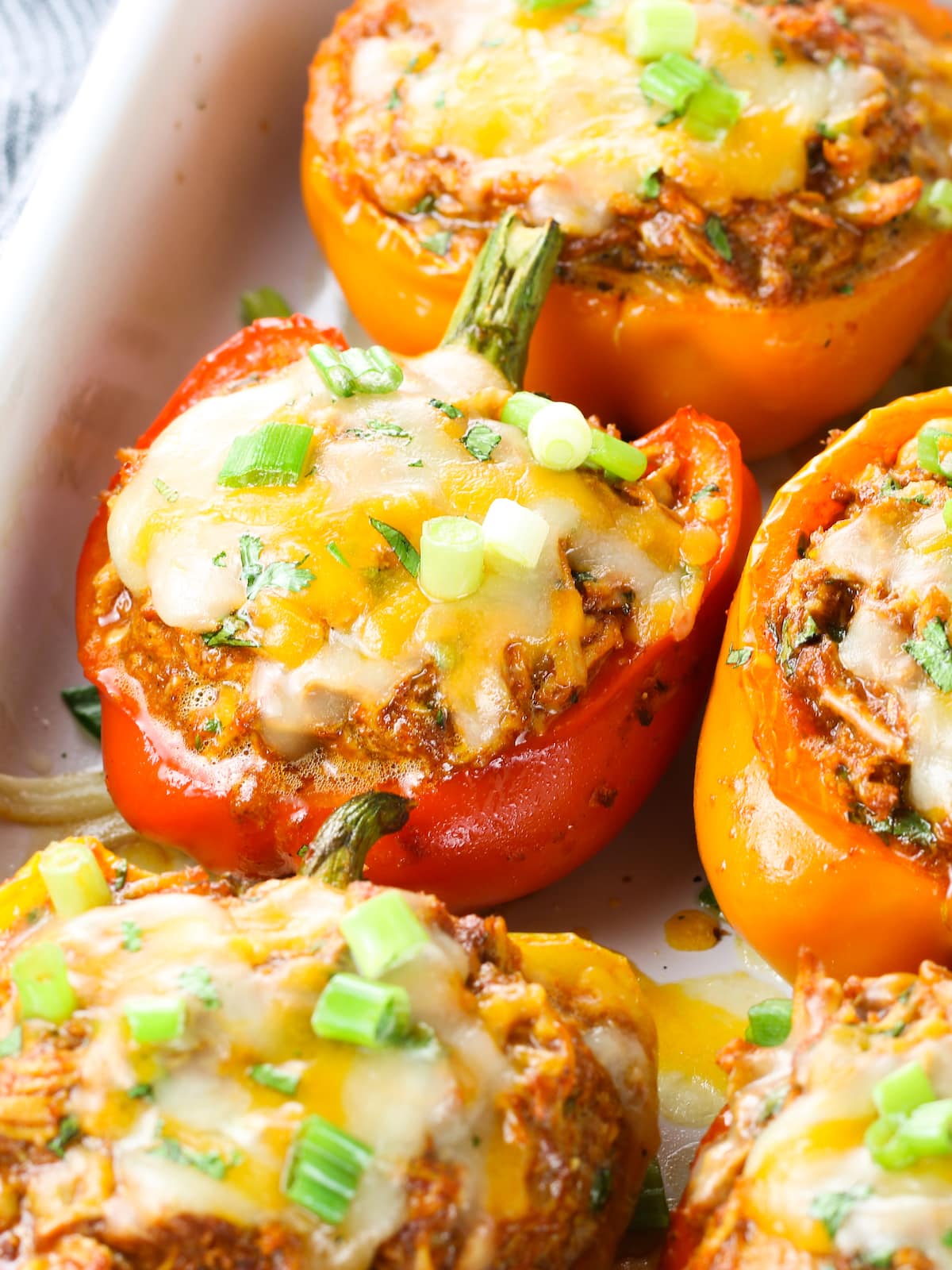 Stuffed peppers cooked topped with melted cheese and sliced green onions.