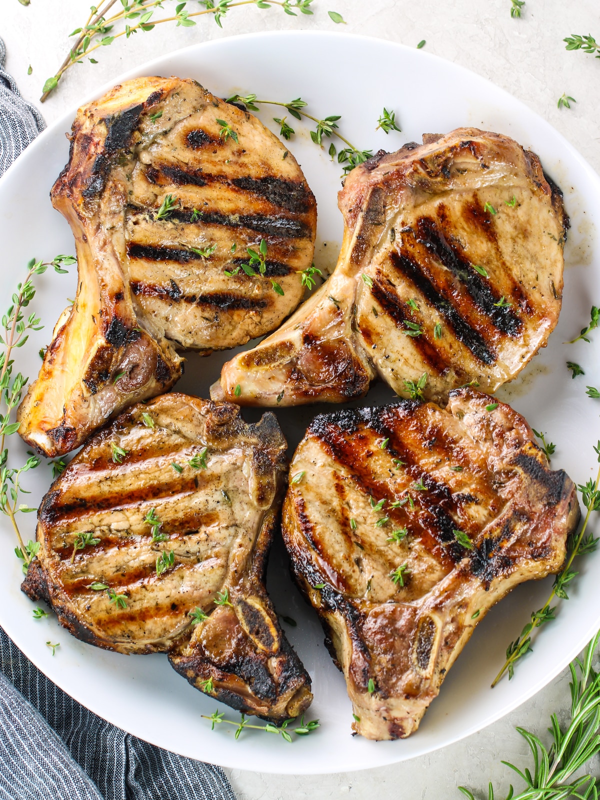 Four grilled pork chops on a plate.