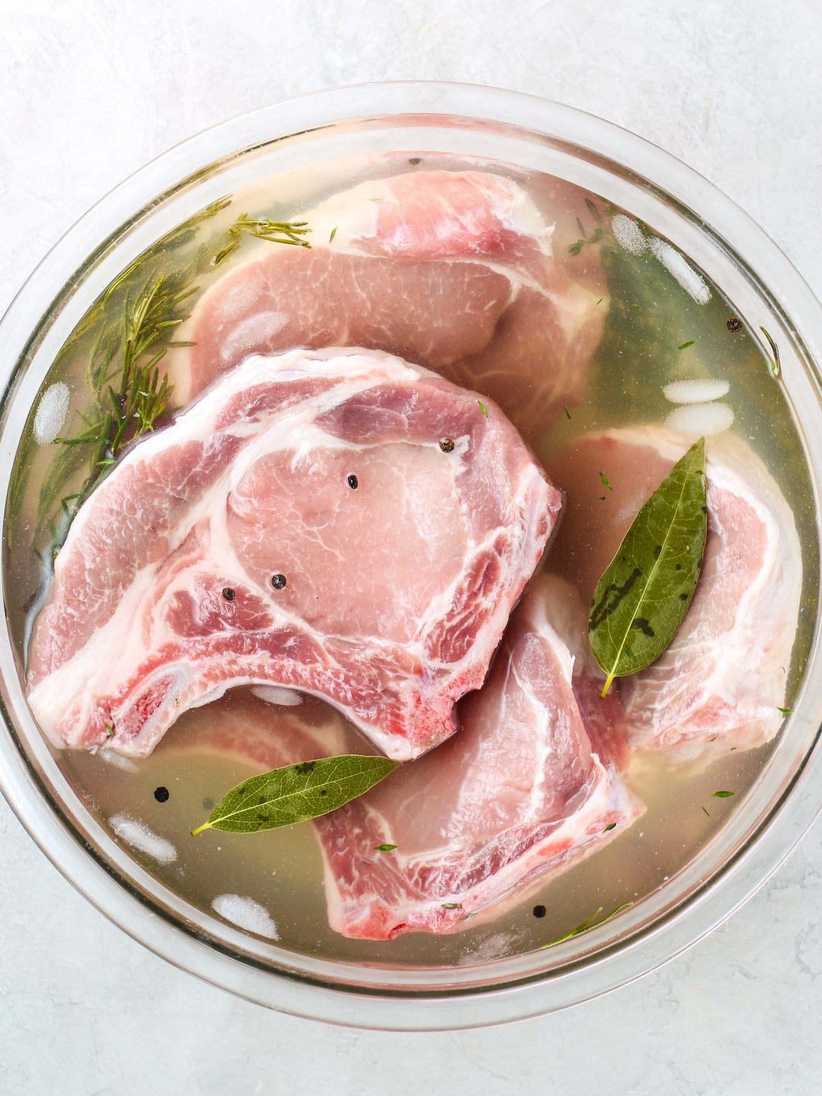 Pork chops in a large bowl with the brine.