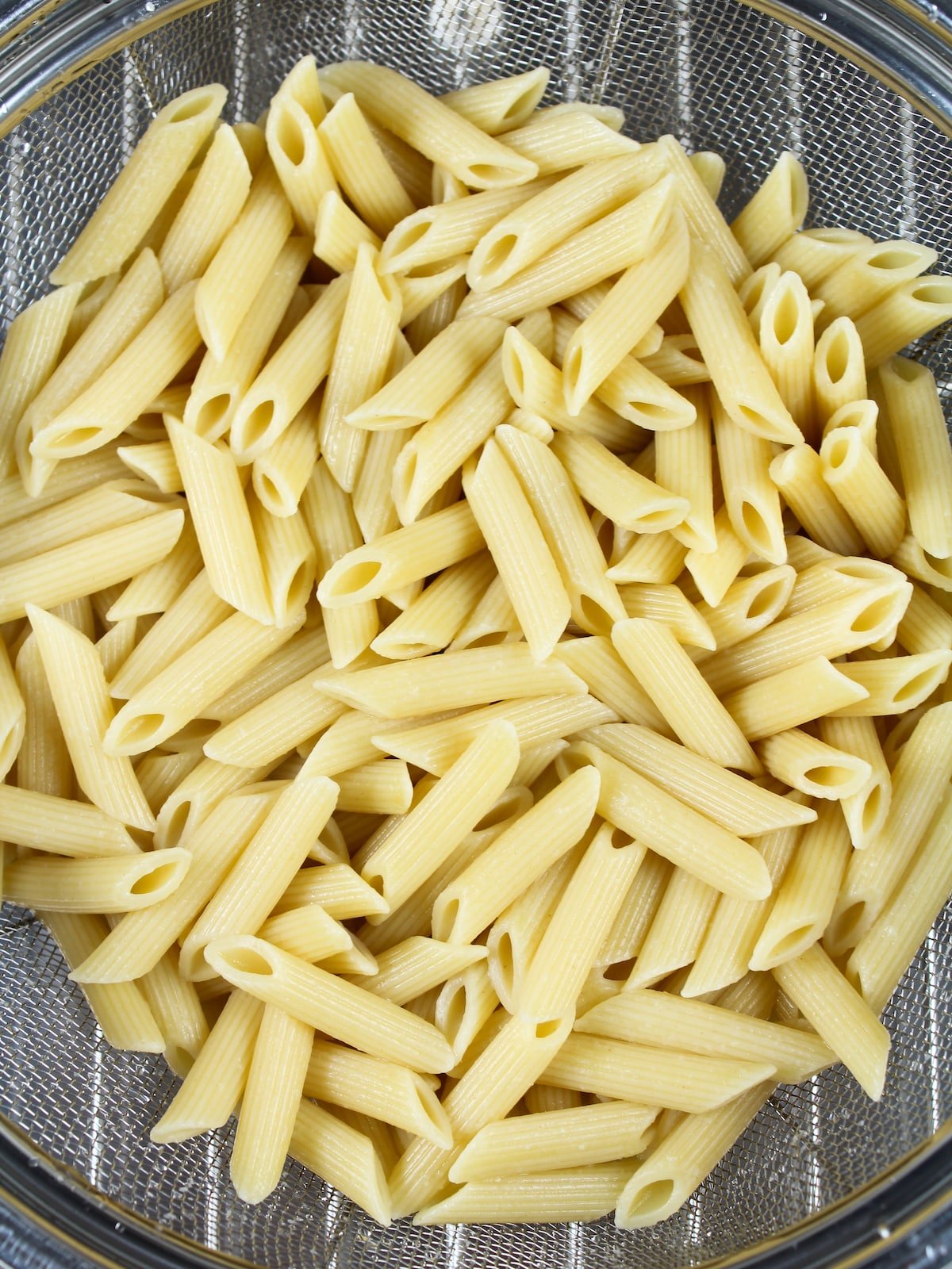 Cooked Penne Pasta draining in a colander.