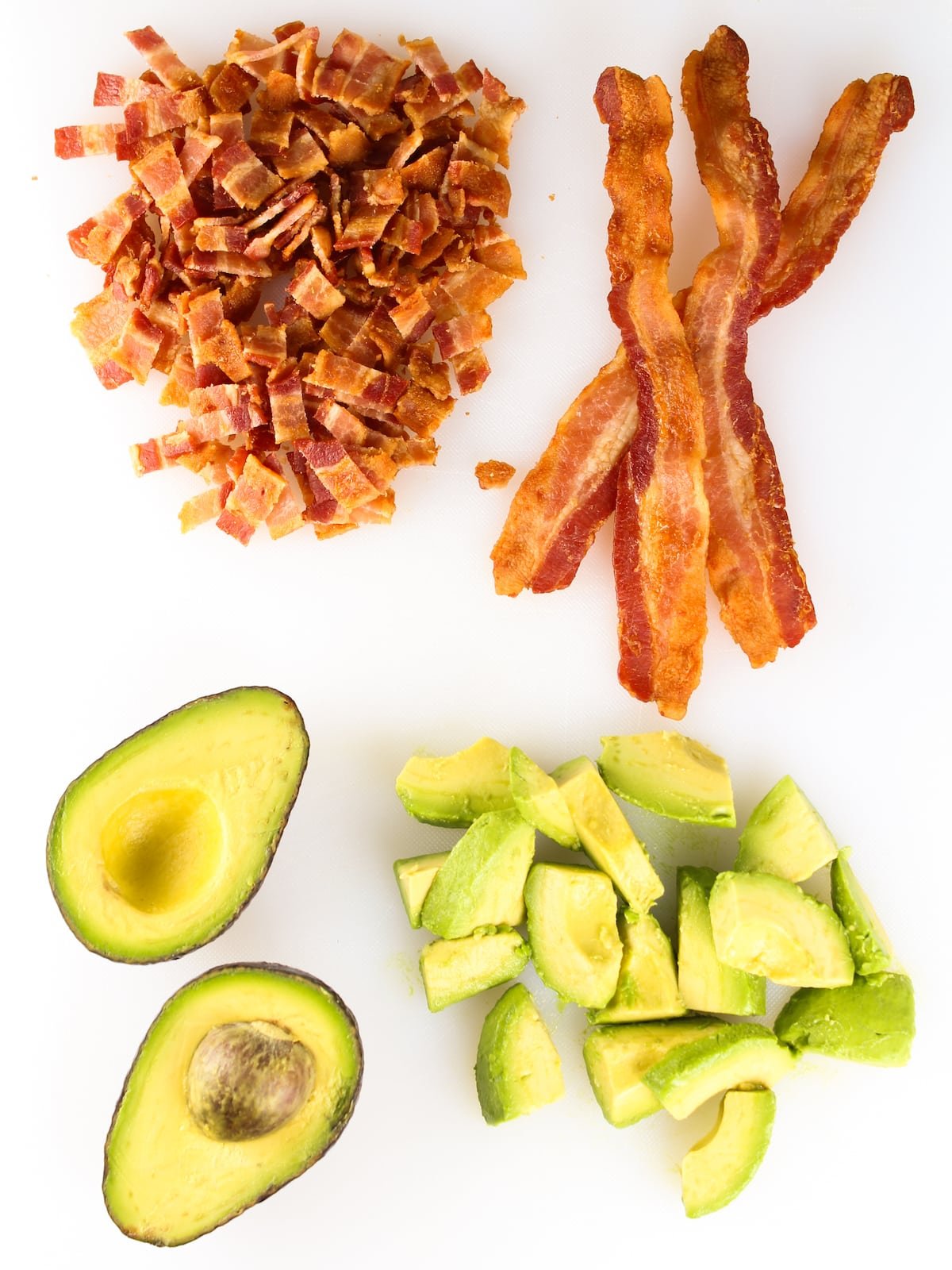 Chopped bacon and sliced avocado on a cutting board.