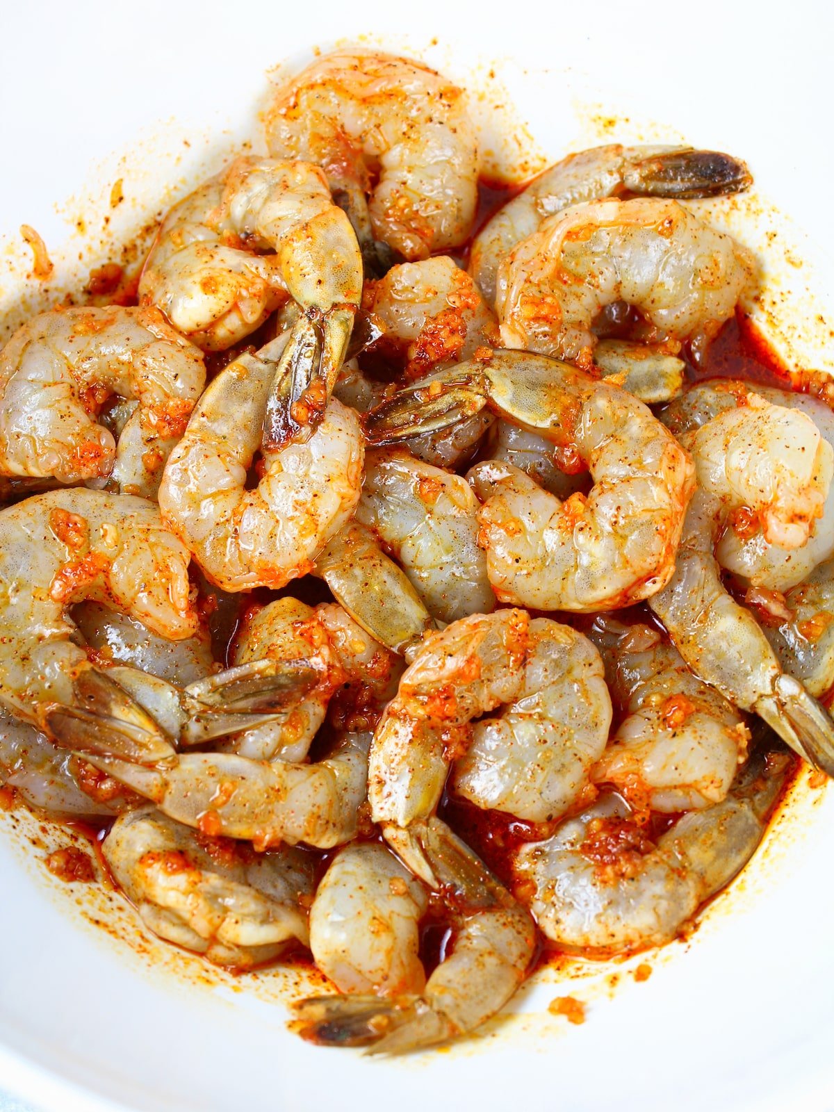 Shrimp in a bowl tossed in the marinade.