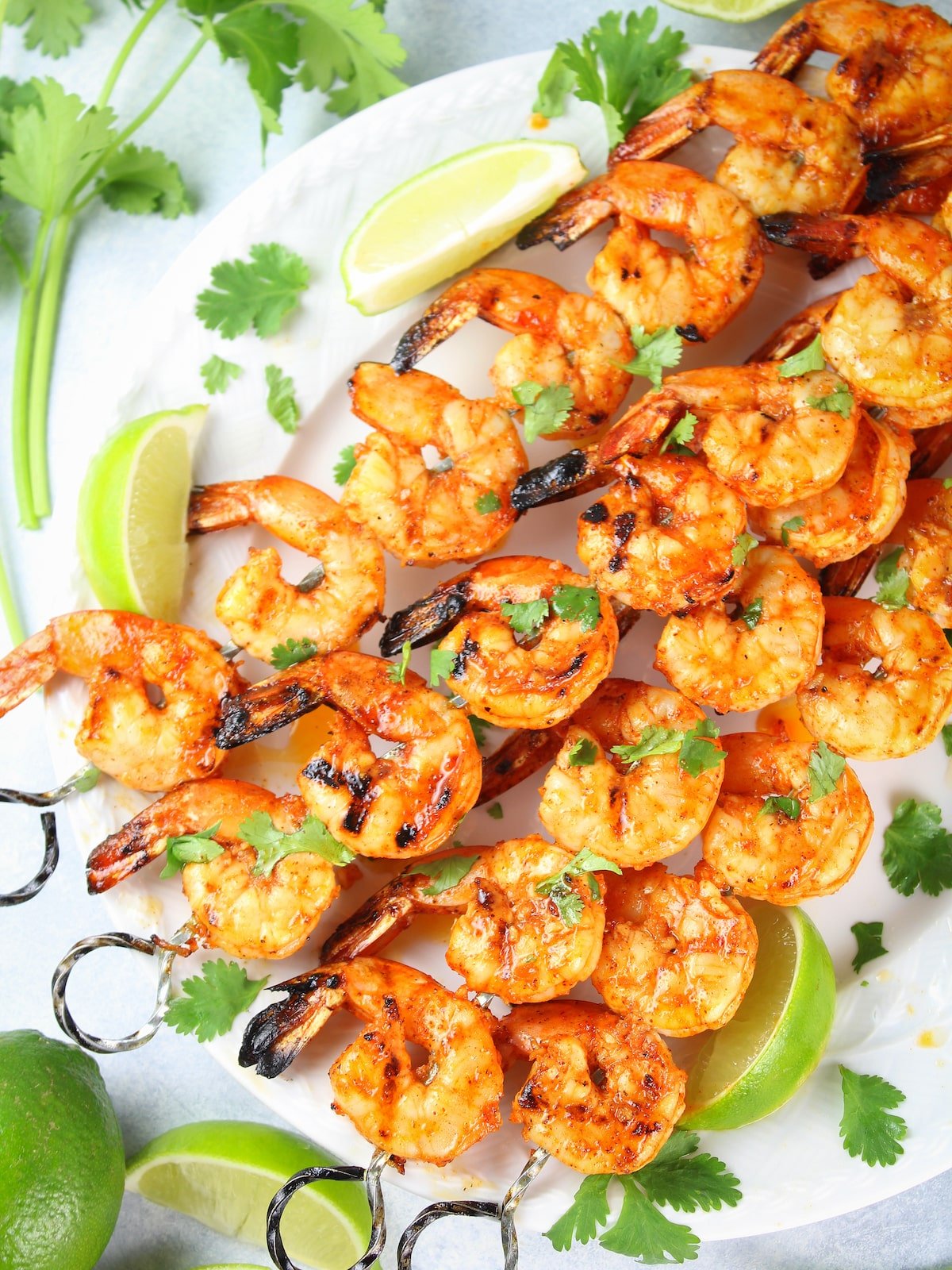 A half platter with cooked shrimp on skewers.