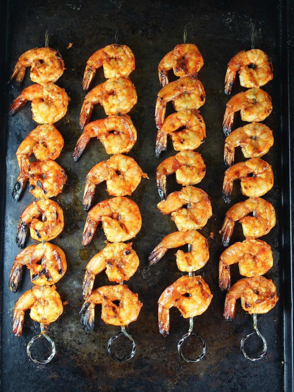 Skewered shrimp on a baking sheet that have been cooked.