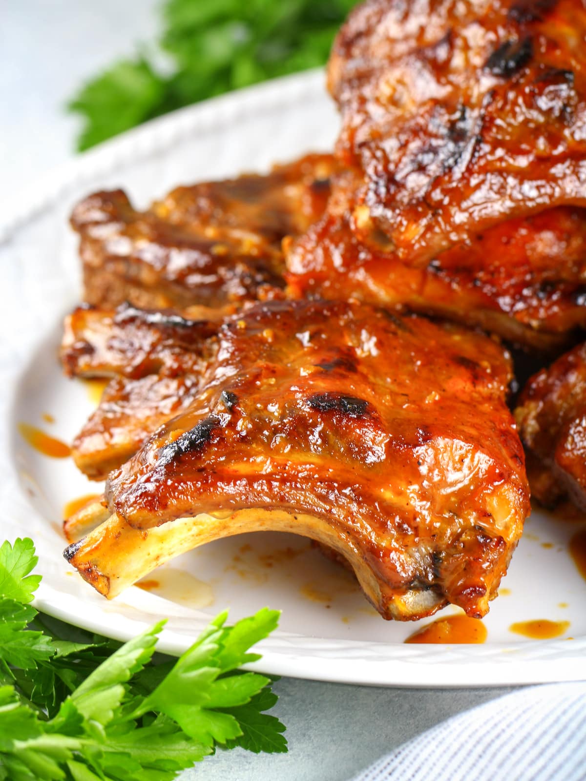 A close-up photo of ribs coated in sauce on a platter.