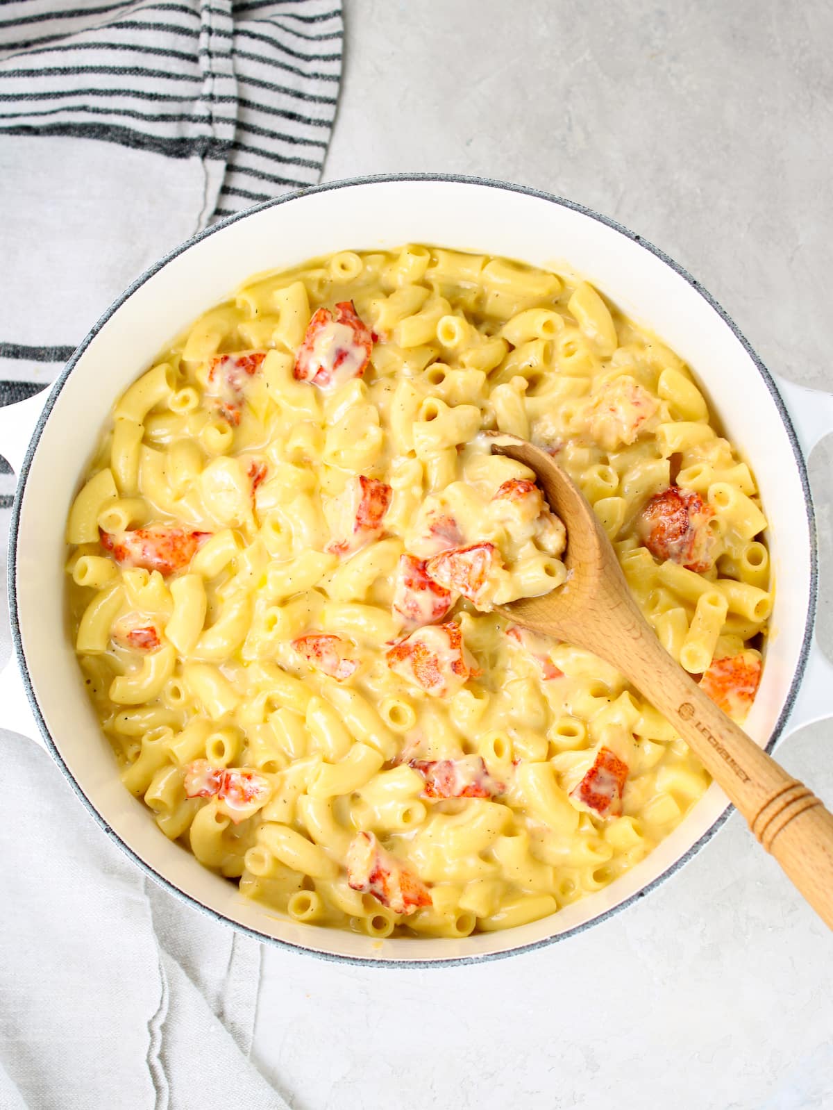 A large pot with melted cheese, macaroni, and lobster.
