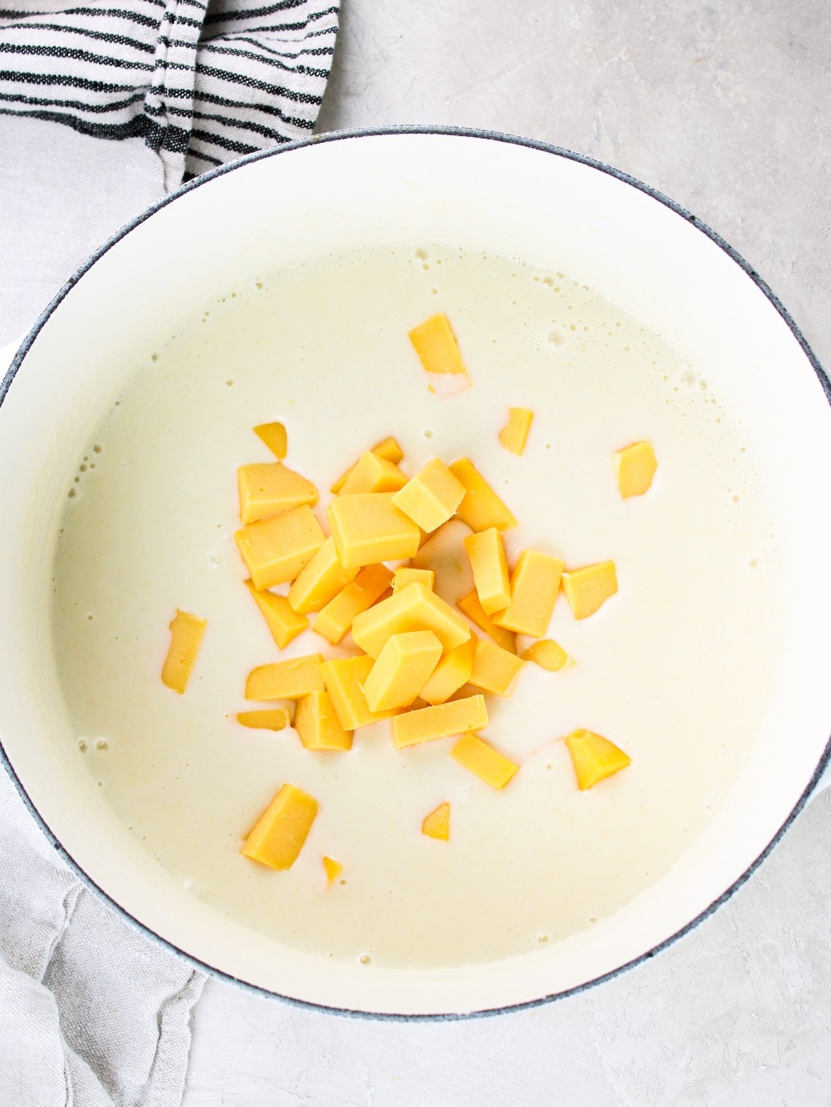 Cubes of American cheese in a pot with milk and flour.