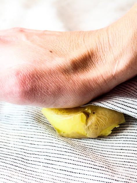 A baby Yukon gold potato on a napkin being smashed.