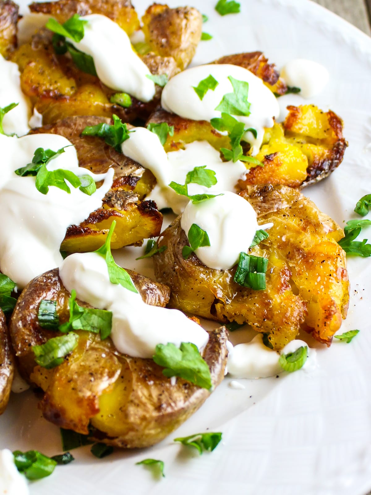 Potatoes on a plate with sour cream and onions.