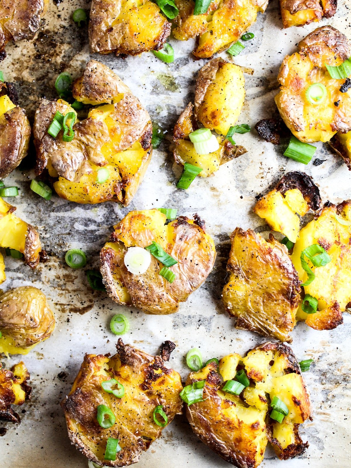 Crispy potatoes on a baking sheet with green onions.