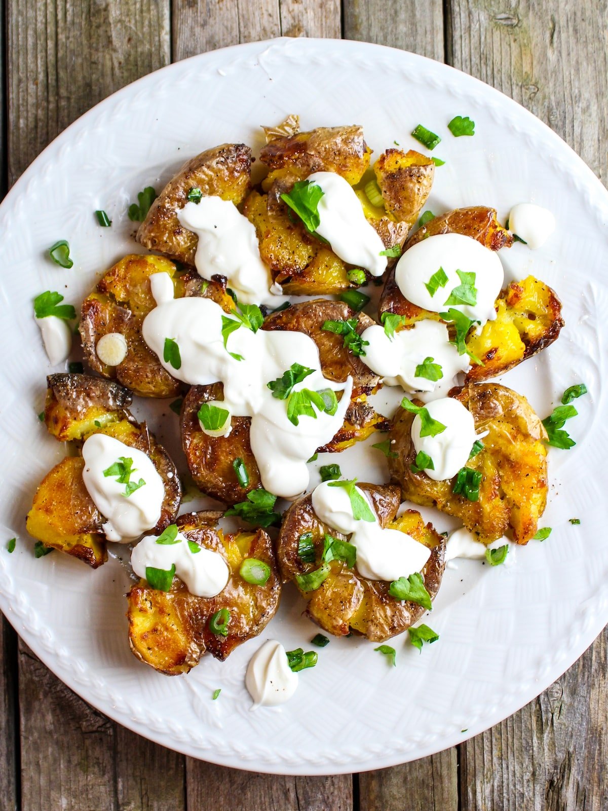 Potatoes on a plate with sour cream and onions.