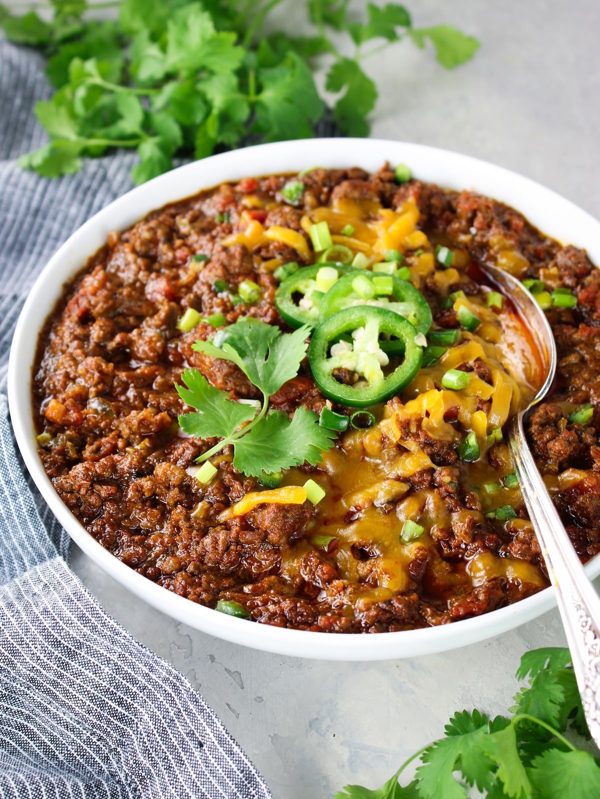 A bowl with a spoon with chili that has no beans.