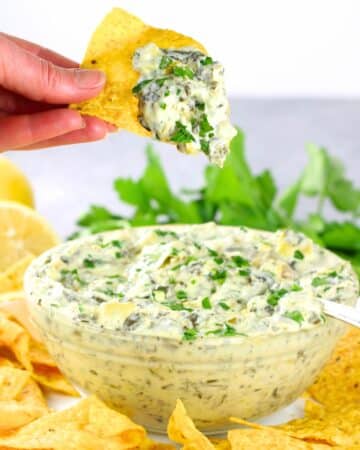 Instant Pot Artichoke Spinach Dip in a bowl with tortilla chips around them.
