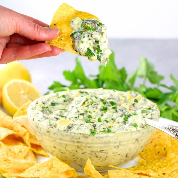 Instant Pot Artichoke Spinach Dip in a bowl with tortilla chips around them.