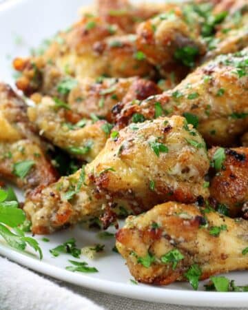 Instant Pot Garlic Parmesan Chicken Wings on a plate sprinkled with parsley.