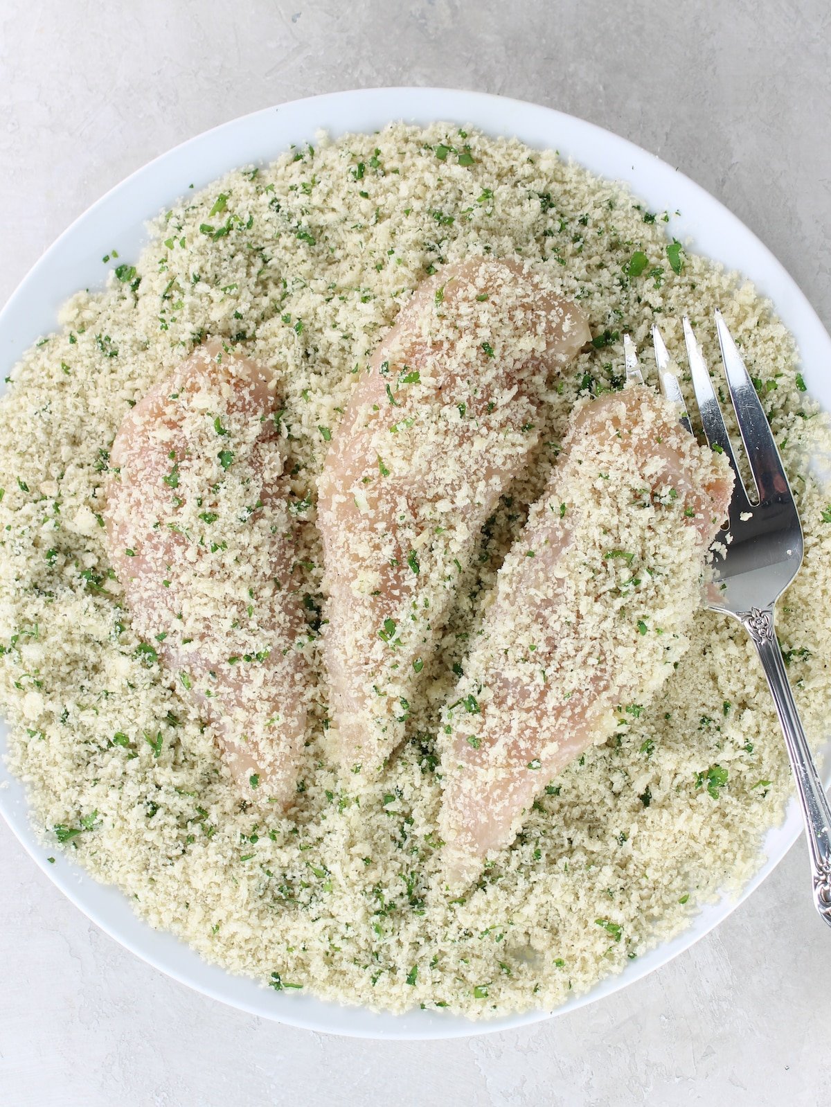 A plate with the meat folded in a mixture of breadcrumbs, parsley and parmesan cheese.