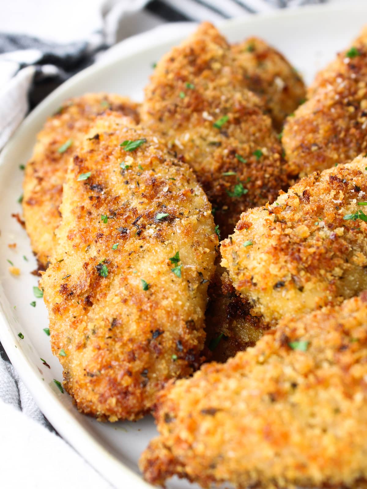 A close-up photo of baked parmesan chicken tenders on a plate.