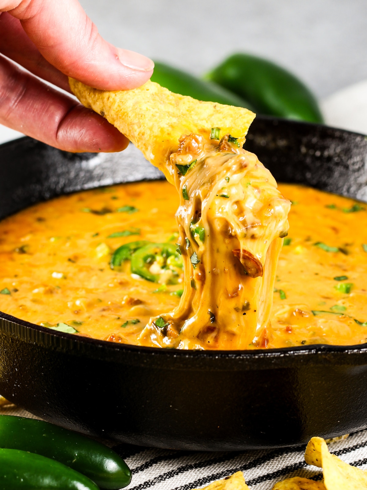 A Closeup photo of a chip being dipped into a skillet of Queso Fundido.