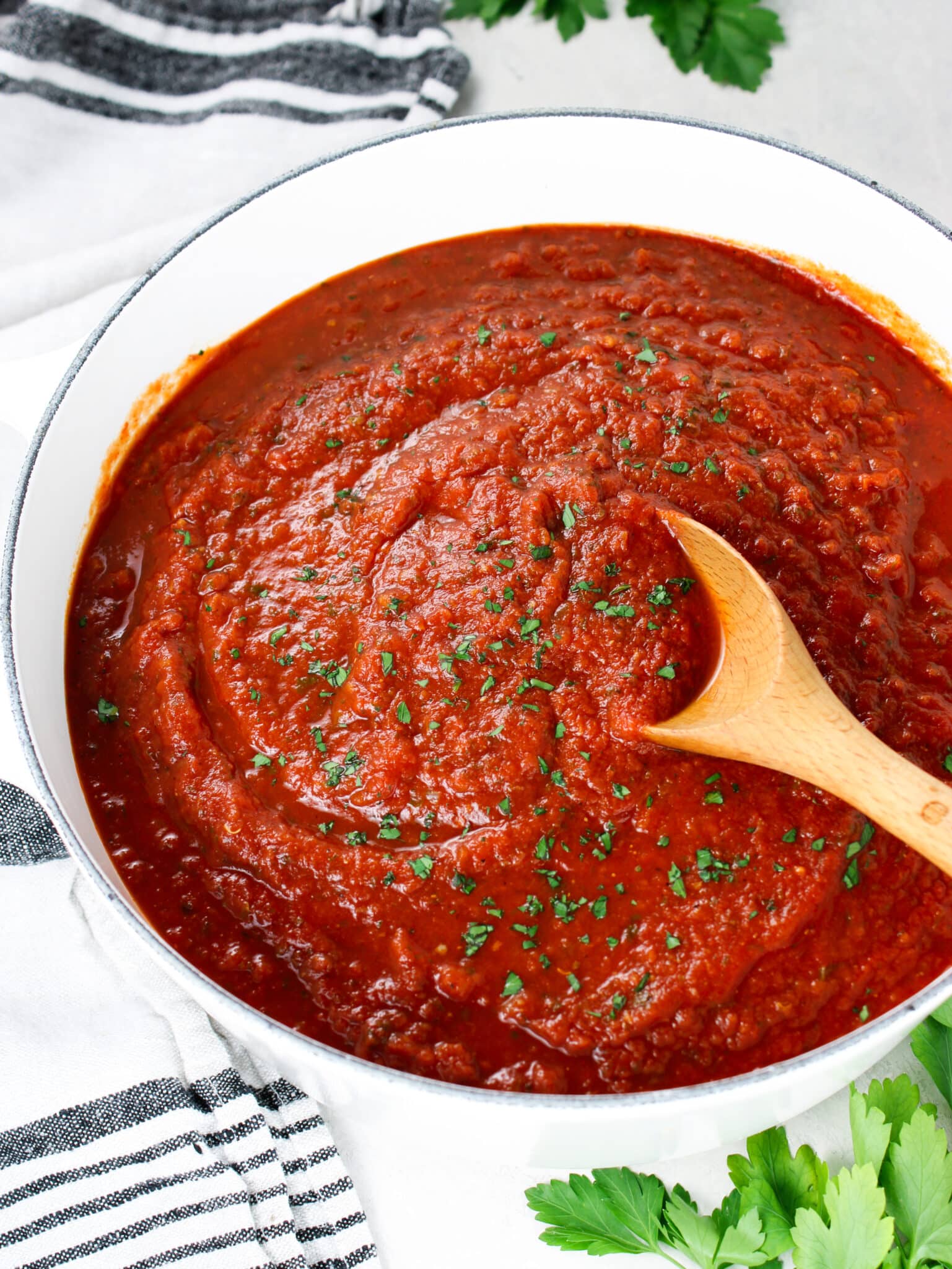 A pot with tomato sauce and a wooden spoon.