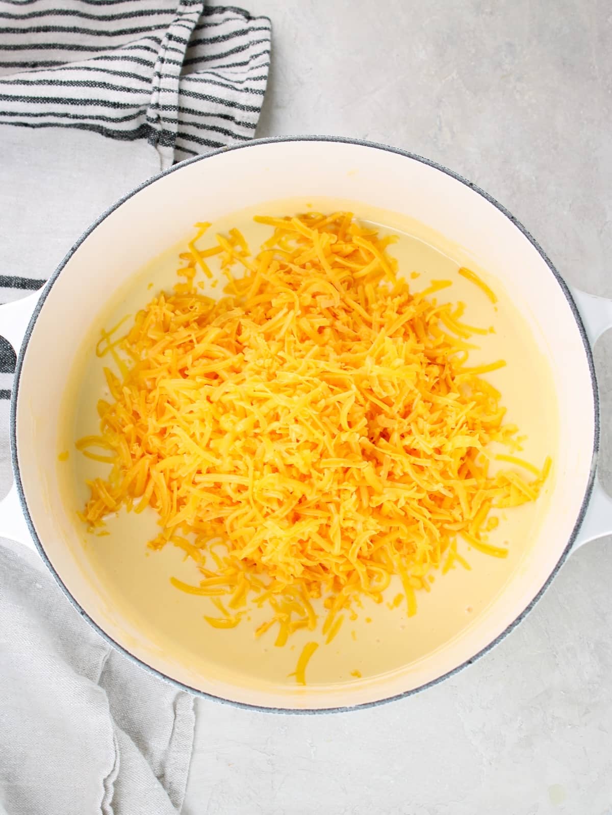 Shredded cheddar cheese added to the pot of ingredients.