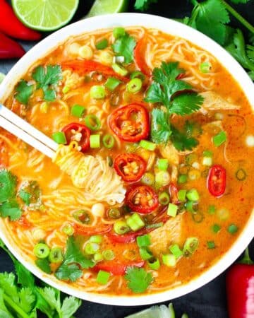 A bowl with noodles, chicken and Thai red curry.
