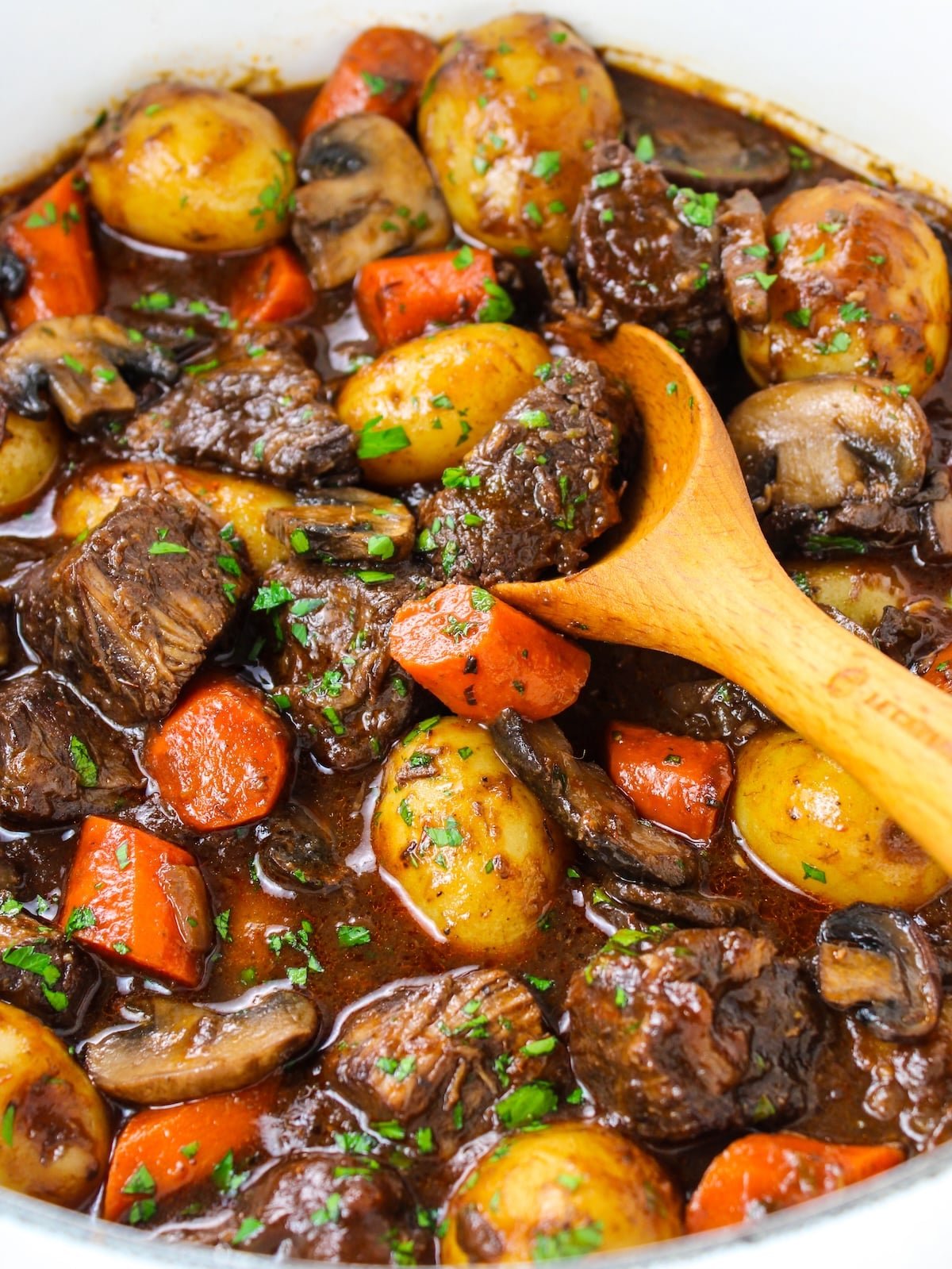 Beef stew in a pot with a wooden spoon.