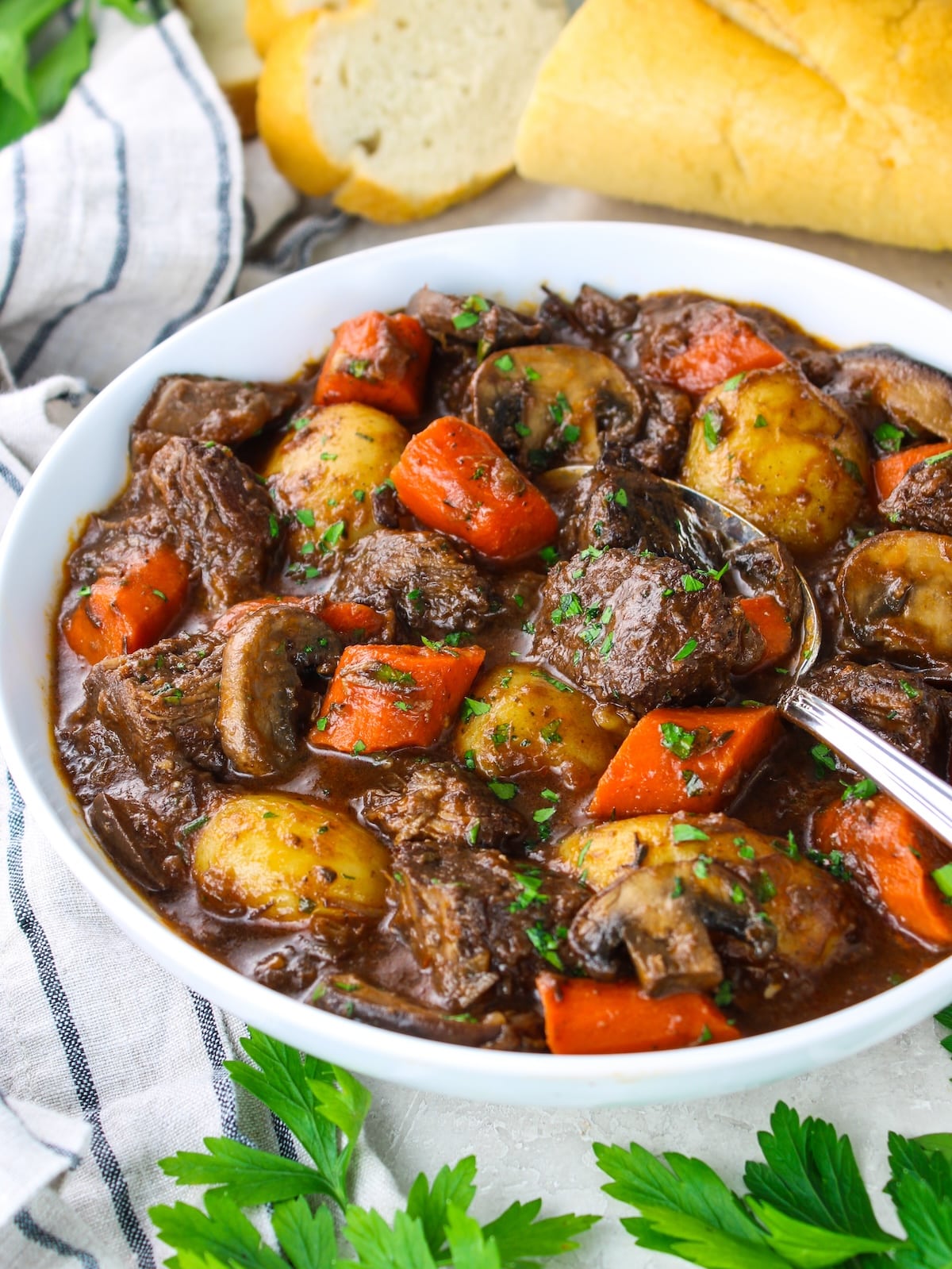 A bowl of stew with bread on the side.