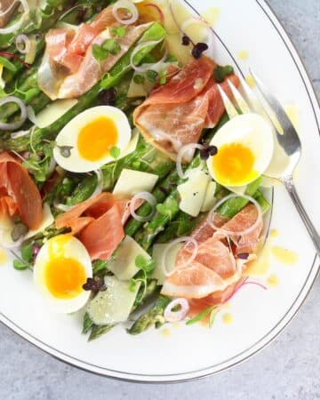 A photo of Asparagus Salad with Prosciutto, Eggs and Dijon Vinaigrette on a platter.