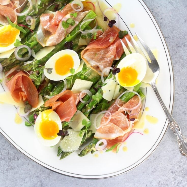 A photo of Asparagus Salad with Prosciutto, Eggs and Dijon Vinaigrette on a platter.