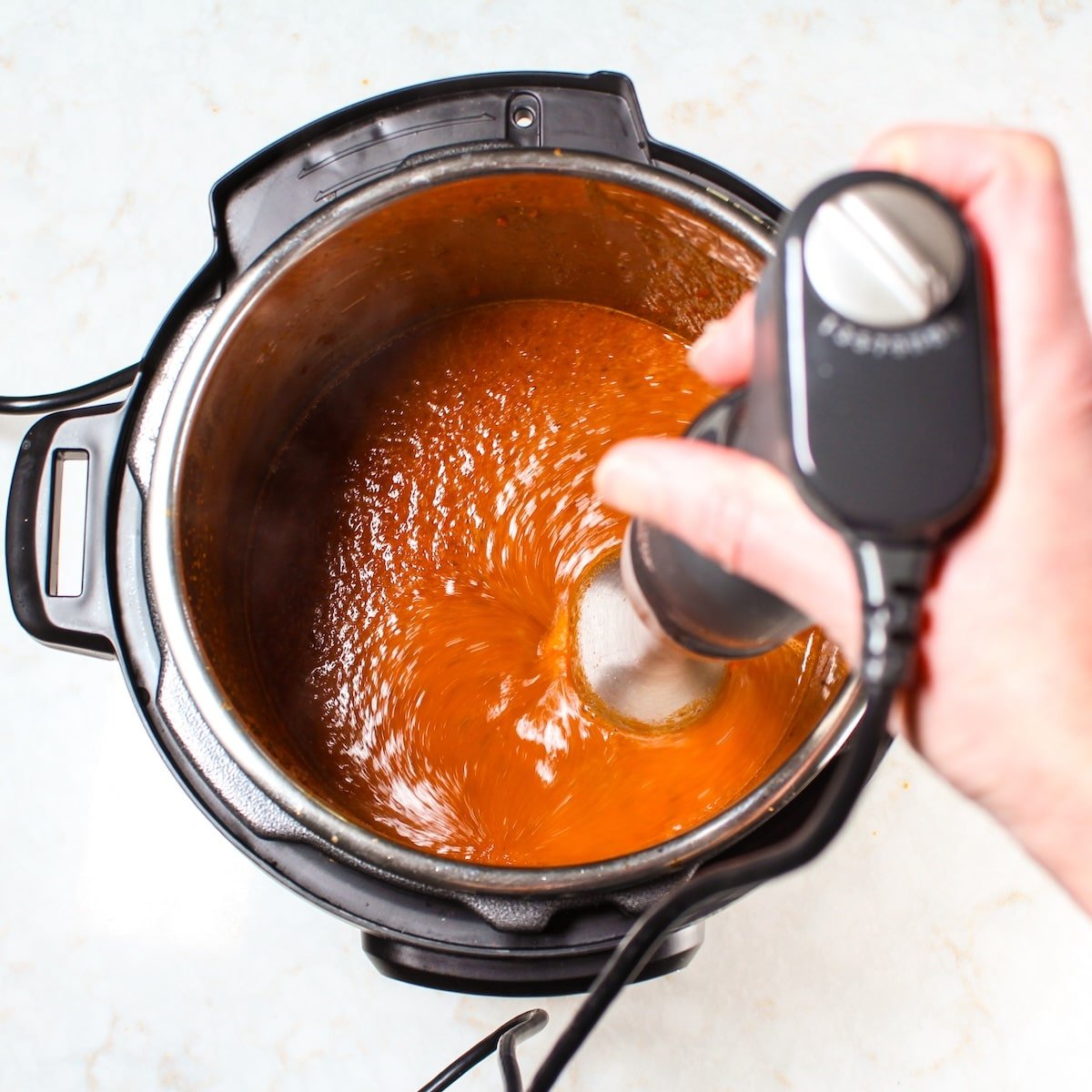 An immersion blender pureeing the sauce.