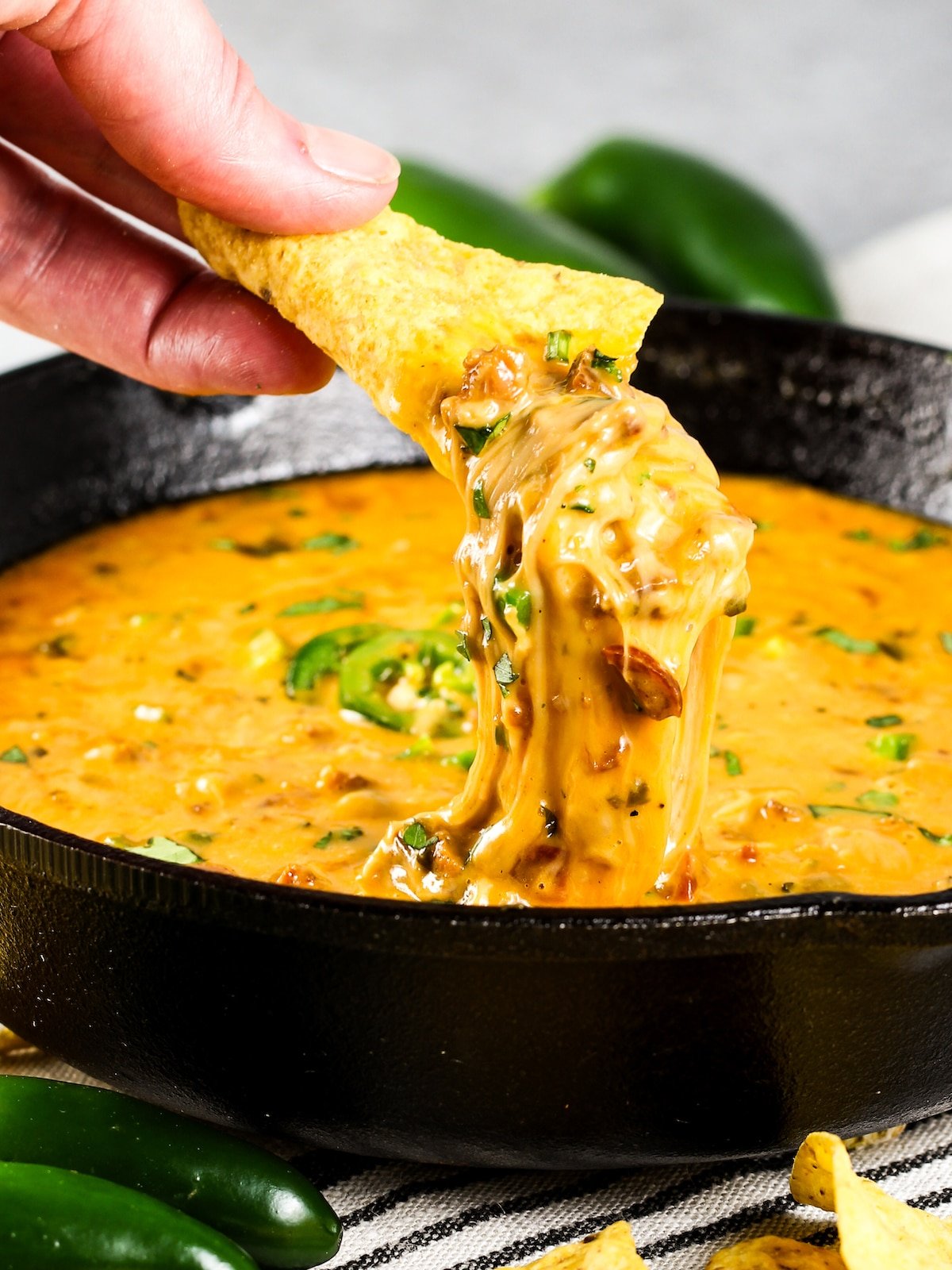 A chip being into a skillet with melted Queso Fundido with Chorizo.