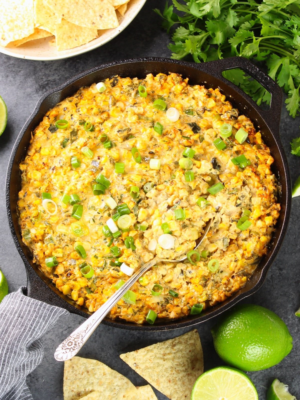 A skillet with Smoky Poblano Corn Dip and chips all around it.