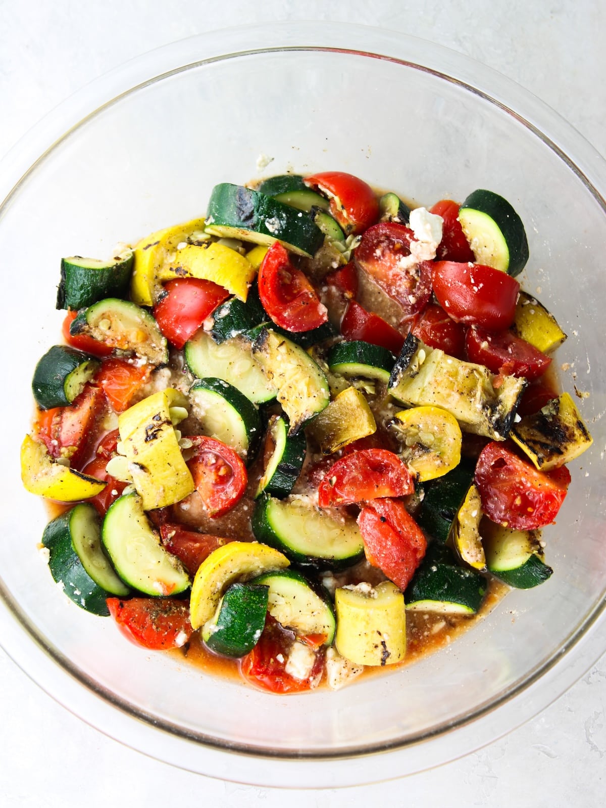 Squash and zucchini added to the bowl of tomatoes with feta.