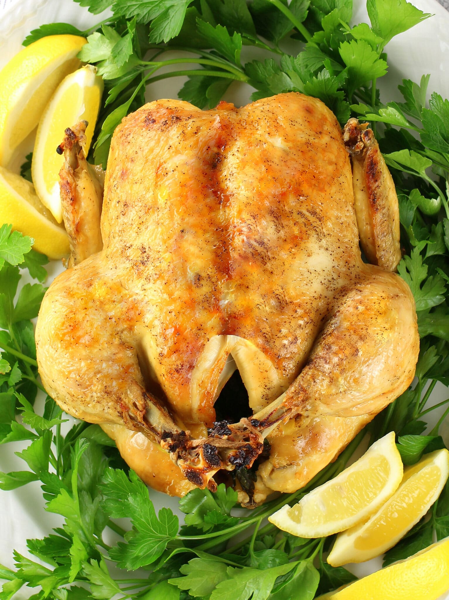 A close-up photo of a whole chicken cooked and browned on a platter.